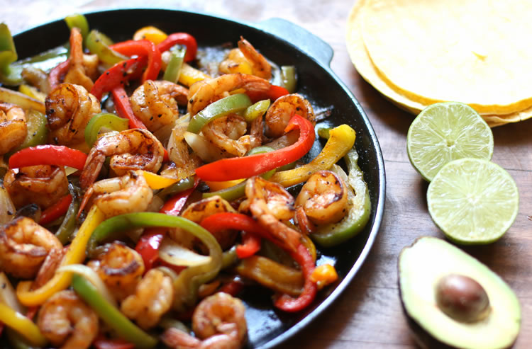 Easy Low Carb Shrimp Fajitas on a skillet next to lime and avocado