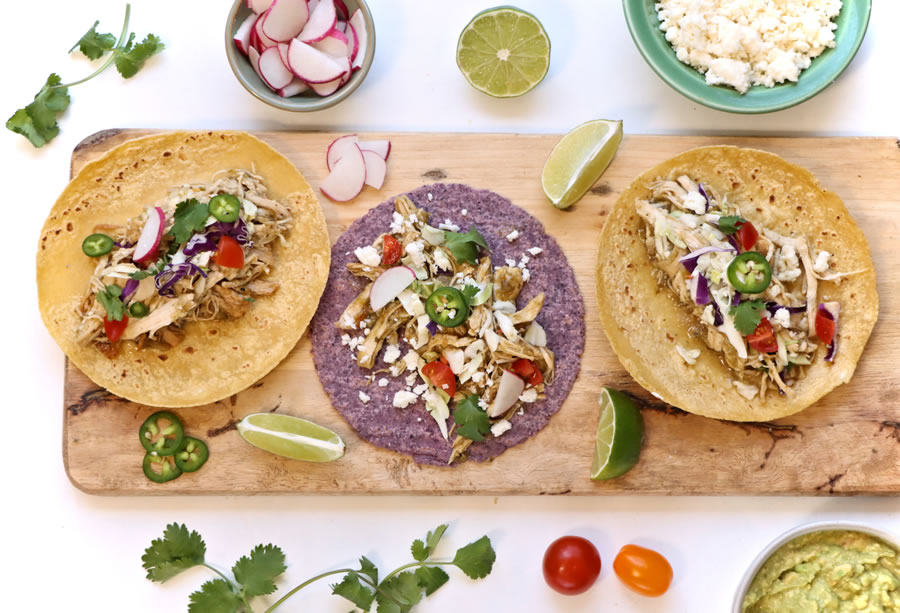 3 Green Chile Chicken Tacos in corn tortillas on a serving board