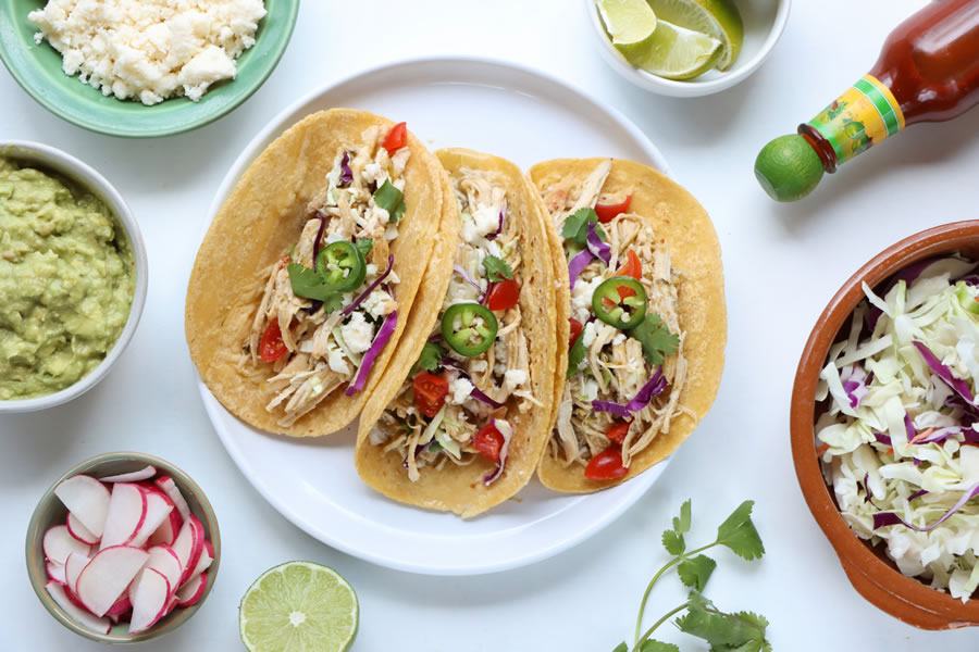 20 Minute Green Chile Chicken Tacos on a plate with cheese tomato cabbage