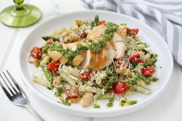 A plate of Gluten -Free Chicken Basil Pesto Pasta with a fork, gray and white striped napkin